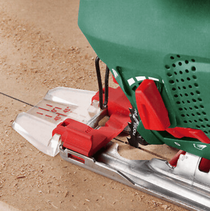 ชายใช้เลื่อยจิ๊กซอว์ไฟฟ้าที่ติดใบเลื่อยสำหรับไม้ กำลังตัดวัสดุไม้ในโรงงาน