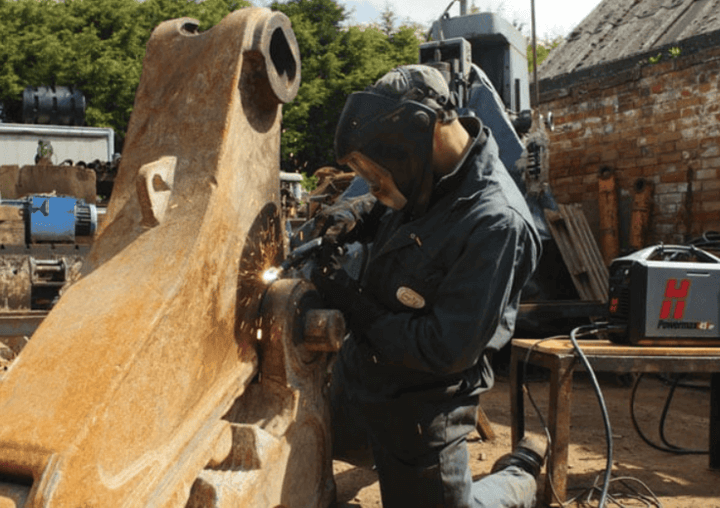 ชายทำงานกับเครื่องตัดพลาสม่านอกอาคาร ตัดโลหะกลางแจ้งด้วยเครื่องมือที่มีประสิทธิภาพสูง