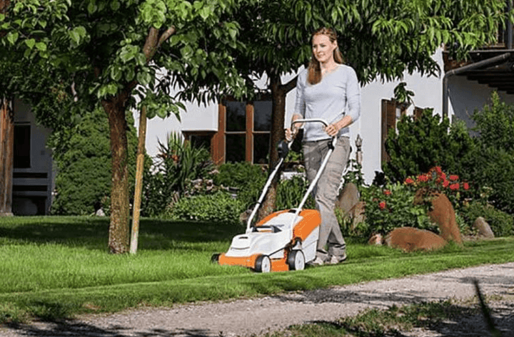 ผู้หญิงใช้เครื่องตัดหญ้าไฟฟ้าแบบไร้สายหน้าบ้าน 