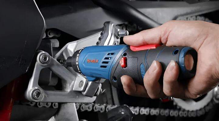 ชายกำลังซ่อมจักรยานด้วยไขควงไฟฟ้า (รุ่นไร้สาย)ในอู่ เขากำลังใช้ไขควงเพื่อขันสกรูบนกรอบจักรยาน พร้อมทั้งเครื่องมือและชิ้นส่วนจักรยานกระจายอยู่รอบตัวเขา