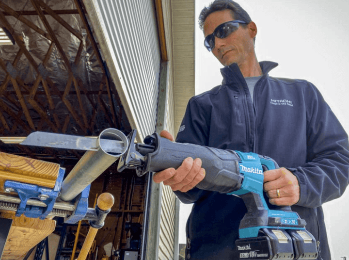 ชายกำลังใช้เลื่อยรีซิโพรคาทิงแบบไร้สายตัดท่อเหล็ก ด้วยพลังจากแบตเตอรี่ ช่วยให้งานตัดมีประสิทธิภาพและความสะดวกสบาย