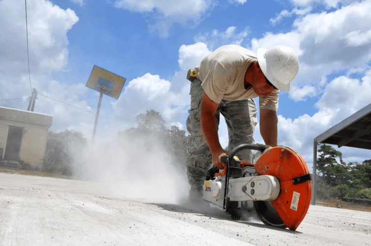 ผู้ชายกำลังใช้เครื่องตัดคอนกรีตตัดถนนคอนกรีต งานก่อสร้างถนนอย่างปลอดภัยและแม่นยำ