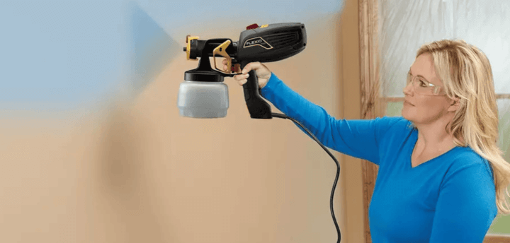 ผู้หญิงกำลังพ่นสีผนังสีฟ้าด้วยกาพ่นสีไฟฟ้า เครื่องมือ DIY สำหรับทาสีที่สะดวกและประหยัดพลังงาน