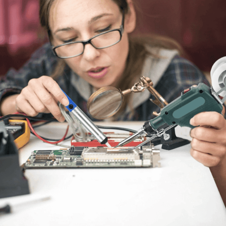 ผู้หญิงใช้หัวแร้งบัดกรีซ่อมแผงวงจรอิเล็กทรอนิกส์อย่างมืออาชีพในห้องทำงาน DIY
