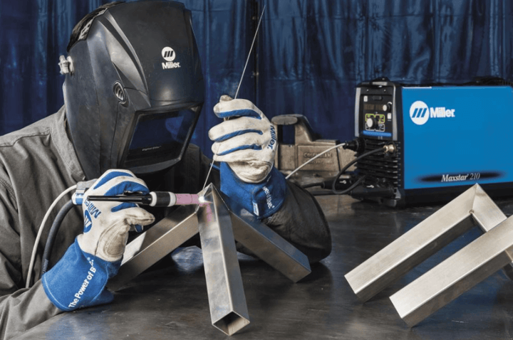 ช่างเชื่อมเหล็กกำลังใช้งานเครื่องเชื่อมเหล็กในเวิร์กช็อป ขณะปฏิบัติงานกับชิ้นส่วนโลหะ